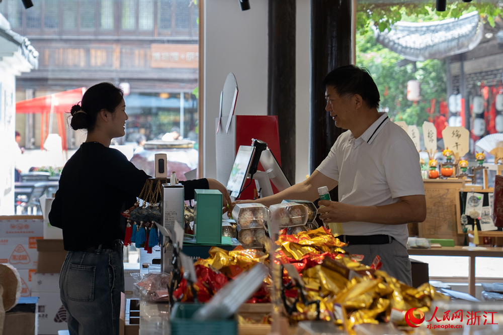 5月26日，浙江省嘉興市月河街上的一處店鋪內，游客在咨詢粽子價格。人民網記者 葛泰佚攝