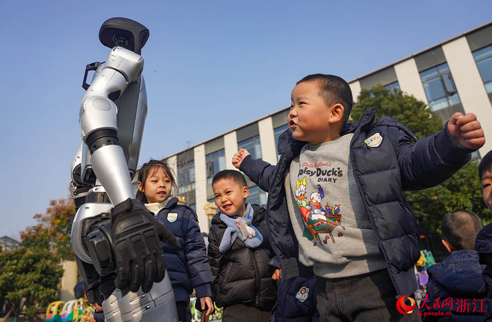 在寧波市江北區慈城懷之幼兒園，小朋友和人形機器人互動。人民網 章勇濤攝